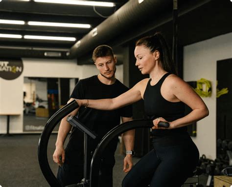 Osobný tréner pomáha klientke s nastavením stroja