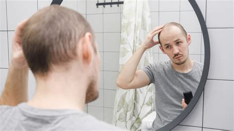 Ilustračná fotografia muža s nadváhou, ktorý sa pozerá do zrkadla s nespokojným výrazom.