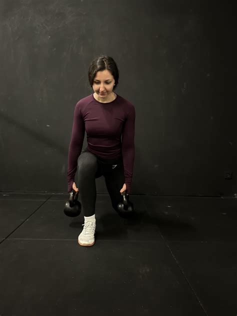 Žena vykonávajúca drep s jednoručnou činkou