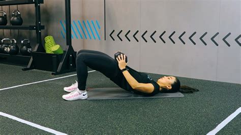 Žena vykonávajúca glute bridge s overballom medzi kolenami