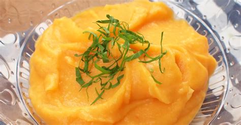 Detailný záber na krémové mrkvové pyré v miske s bylinkami
