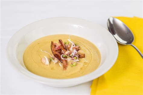 Detailný záber na tradičný demikát v hlinenom tanieri zdobený čerstvou pažítkou a opečenou slaninou