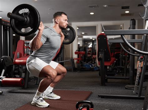 Muž vykonávajúci drep s veľkou činkou.