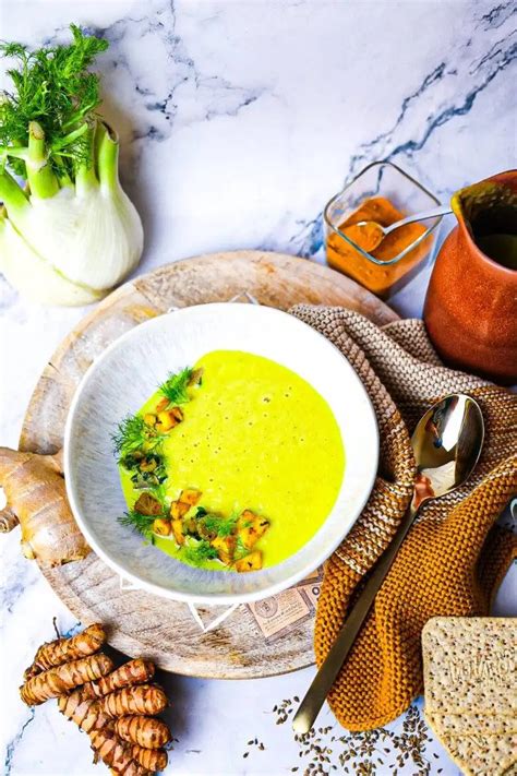 Misku žltej tekvicovej polievky s kurkumou posypanú tekvicovými semienkami.